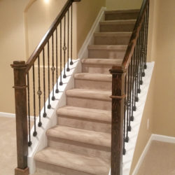 Open stairway with wood railing and newel post in Brothers finished basement