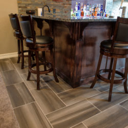Detail of custom wet bar wood work with porcelain tile floor and granite counter in finished basement