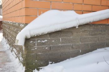 exterior brick foundation and wall corner covered in snow